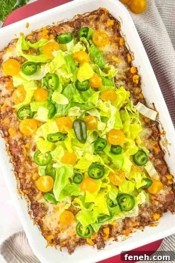 The casserole topped with shredded lettuce, diced tomatoes, and sliced jalapeno peppers.
