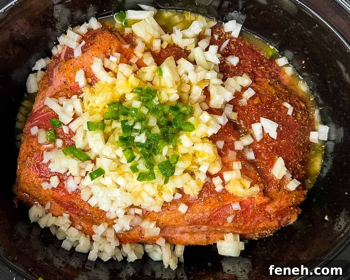 The seasoned pork shoulder in a slow cooker with the rest of the ingredients.
