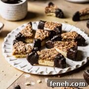 Nussecken bars dipped in chocolate on a white fluted plate.