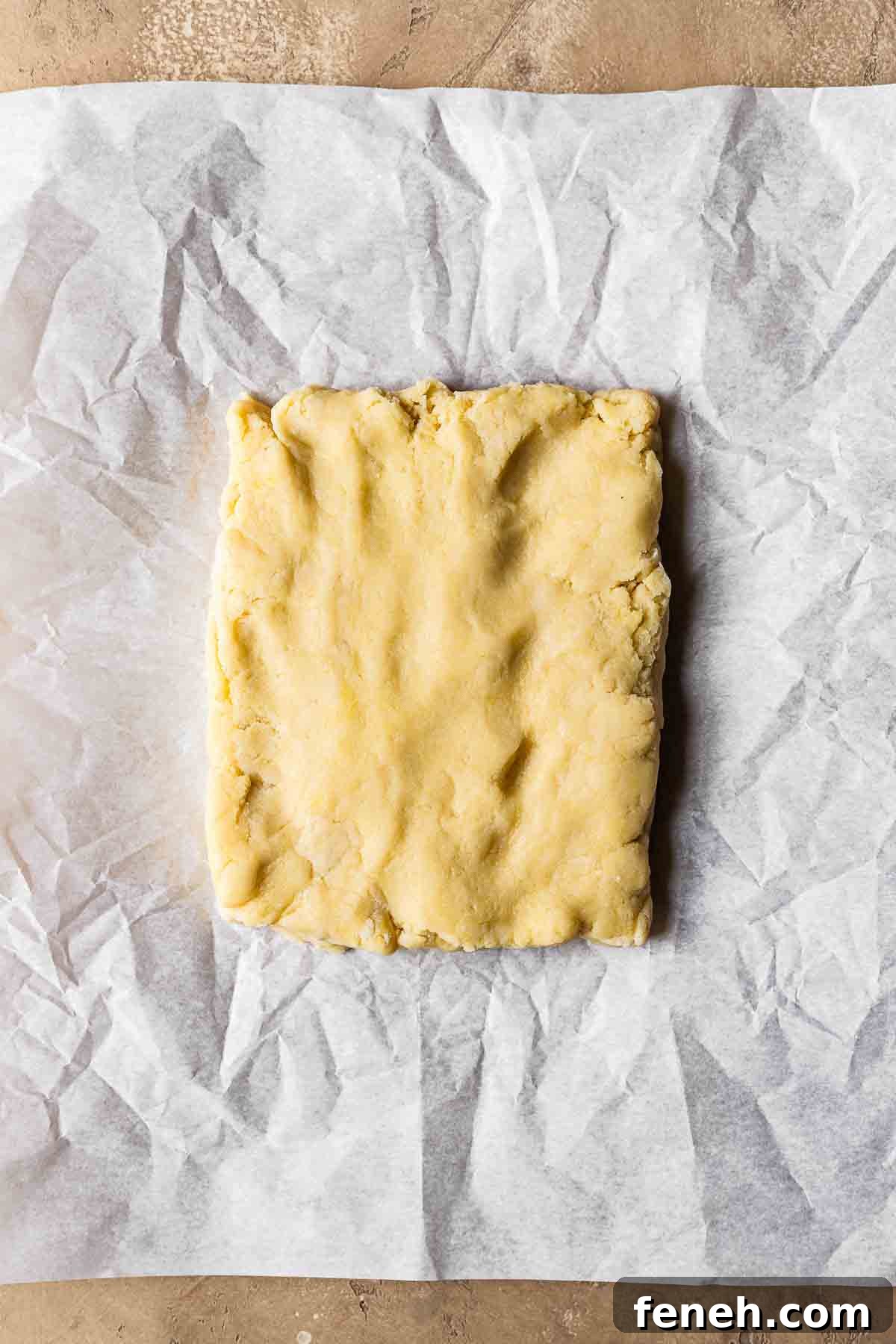 Dough for nussecken shaped into rectangle on white parchment paper.