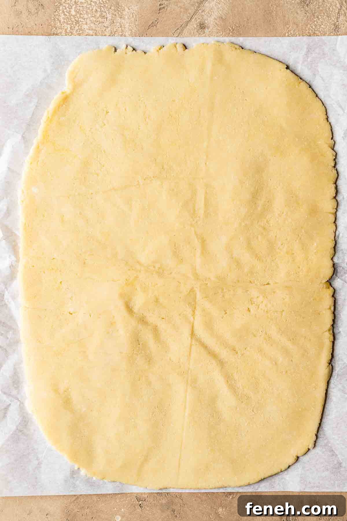 Shortcrust pastry dough rolled out on a piece of parchment paper.