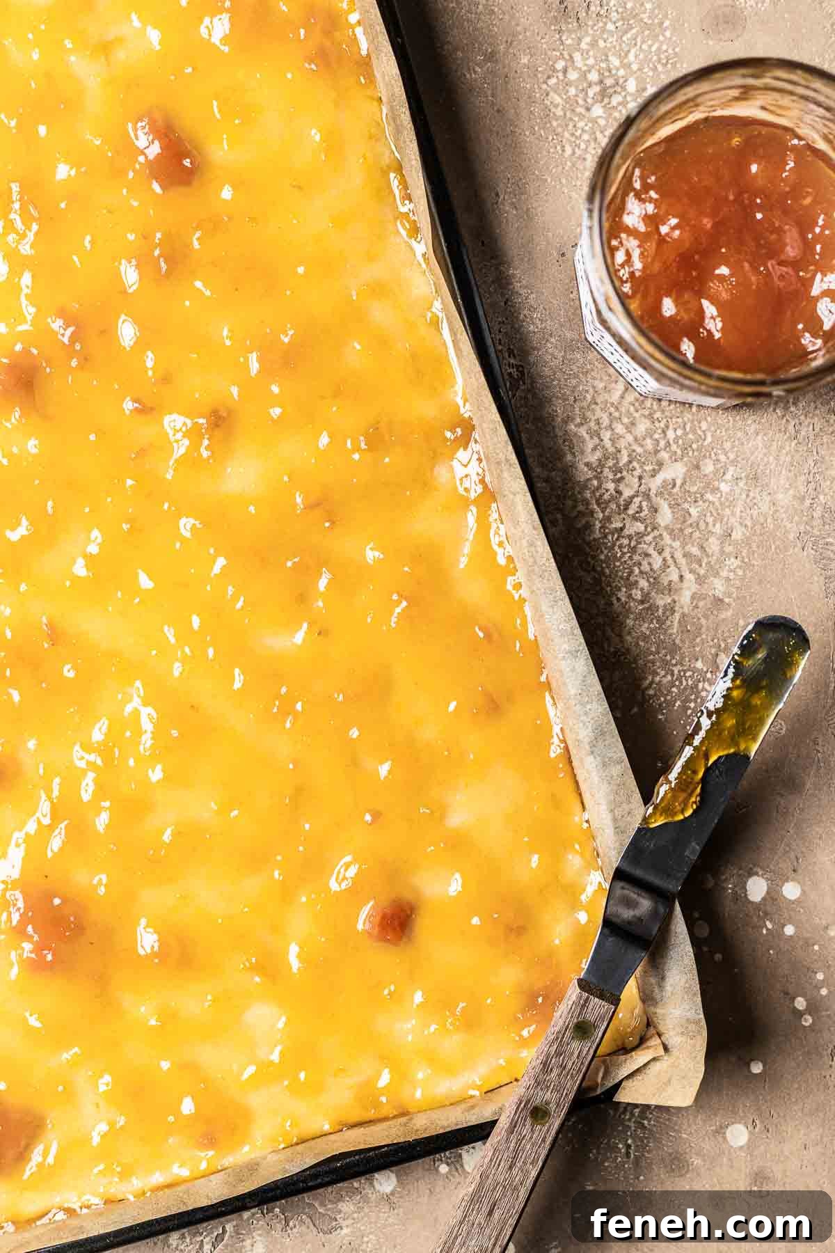 Apricot jam spread over a pan filled with shortcrust pastry dough.