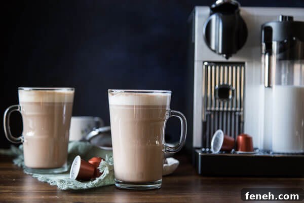 Two tall mugs of chocolate hazelnut latte next to a Nespresso machine