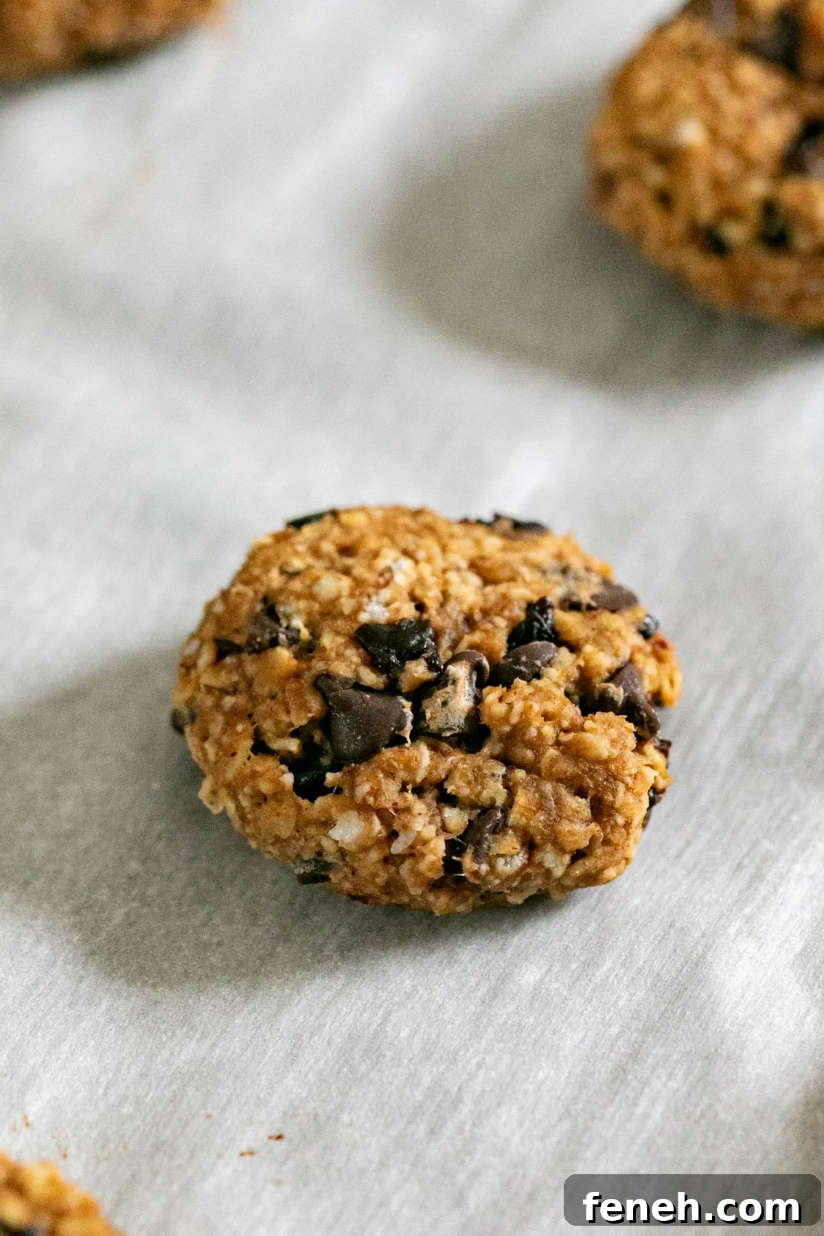 A close up of a single breakfast cookie on a lined pan.
