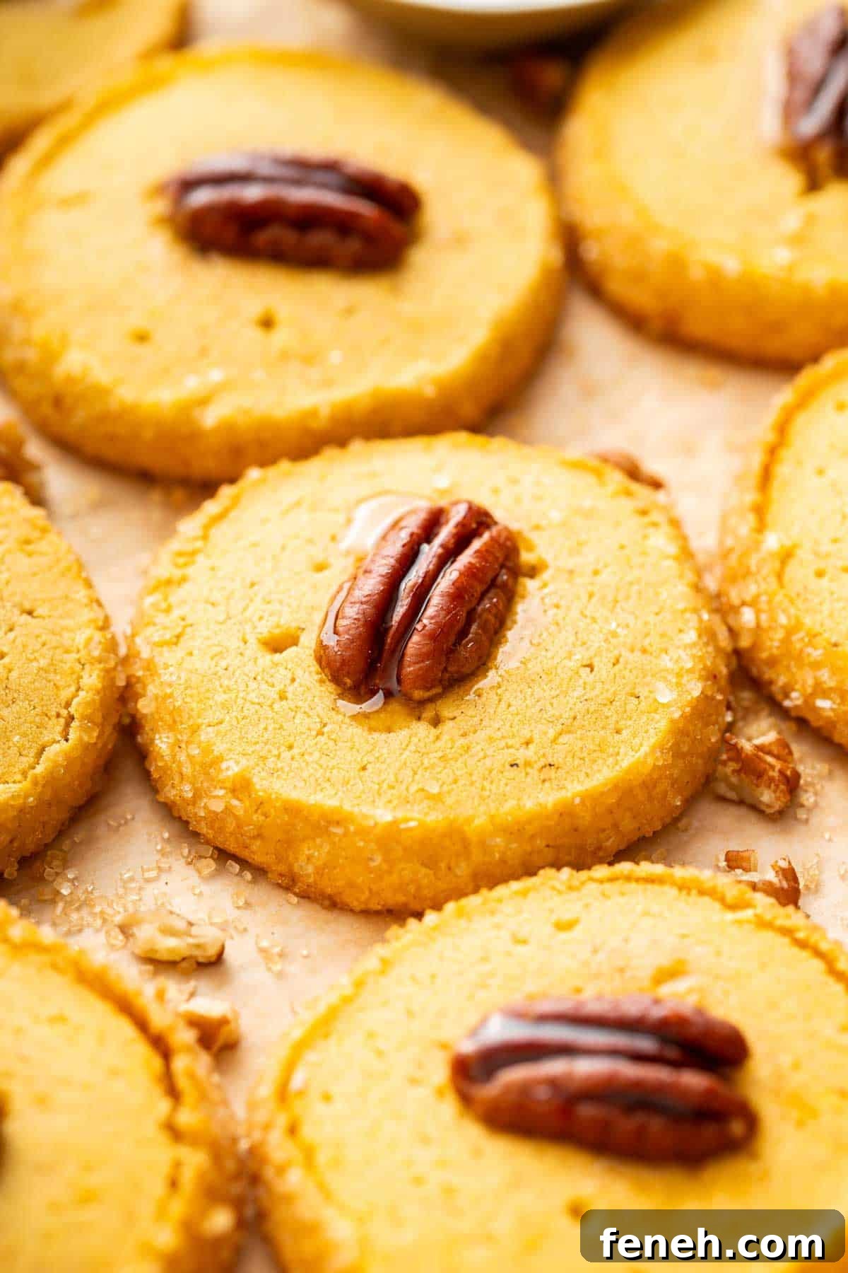 Orange pumpkin shortbread with a glazed pecan on top of each cookie.