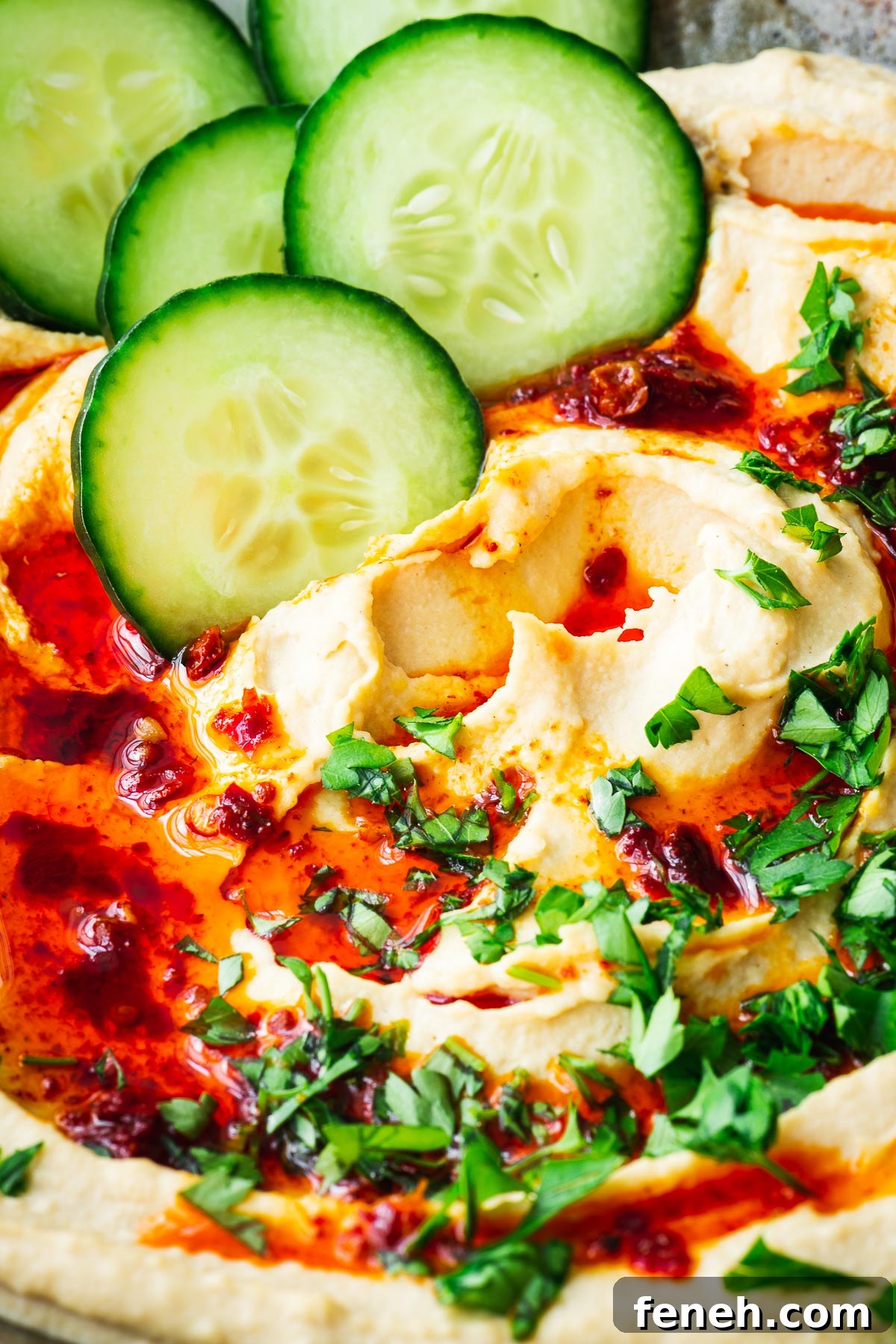 Fluffy hummus drizzled with harissa oil and served with cucumber slices.