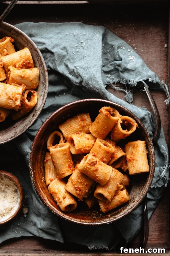 A sun dried tomato pesto pasta into a bowl on green napkin