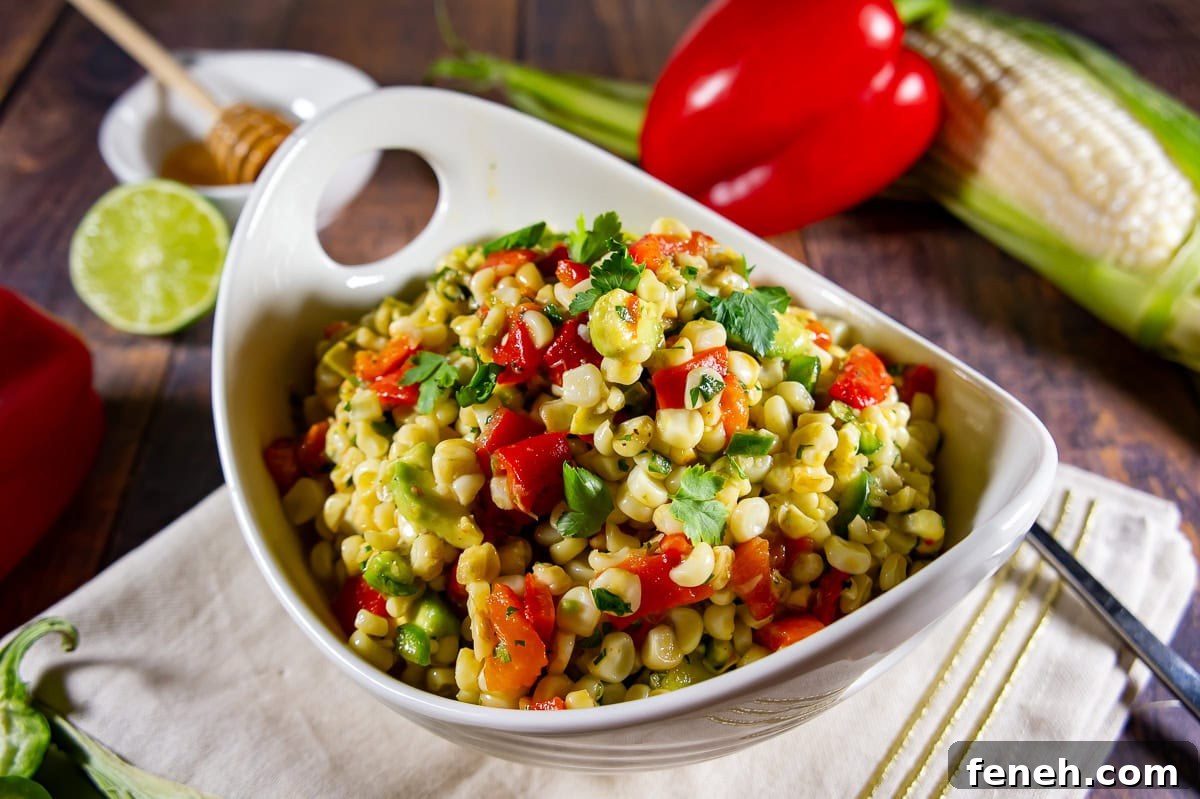 a bowl of corn and avocado salad with roasted red peppers,