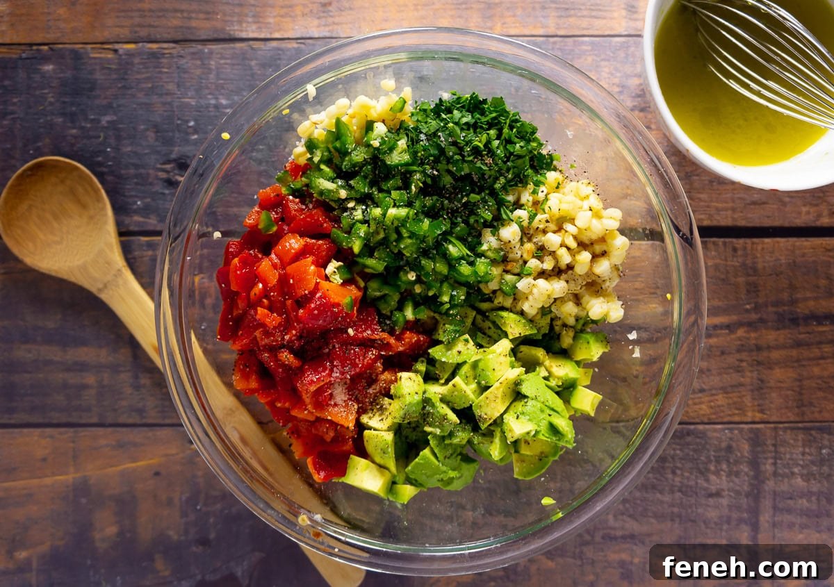 a bowl of chopped corn, avocado, peppers, jalapenos, and herbs.