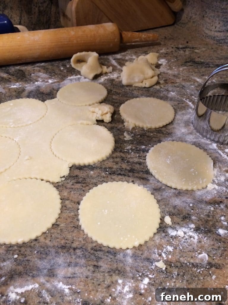 closeup side view: dough rolled thin on a lightly floured surface being cut with cookie cutter