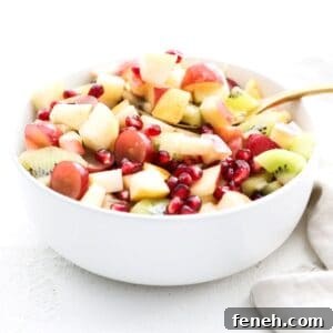 A holiday salad in a white serving bowl with a gold serving spoon.