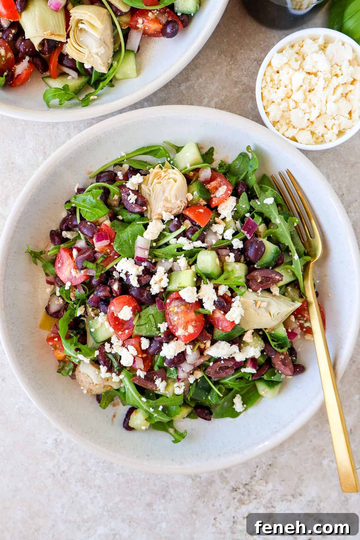 Black bean salad in two bowls with feta on the side.