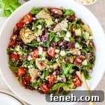 Black bean salad in a bowl with a gold spoon. Balsamic jug, basil, feta and bowls on the side.
