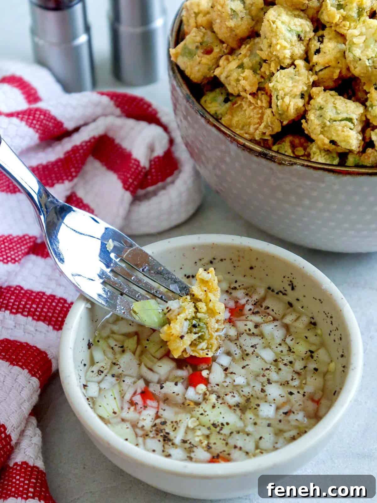 dipping fried okra in spiced vinegar with a fork