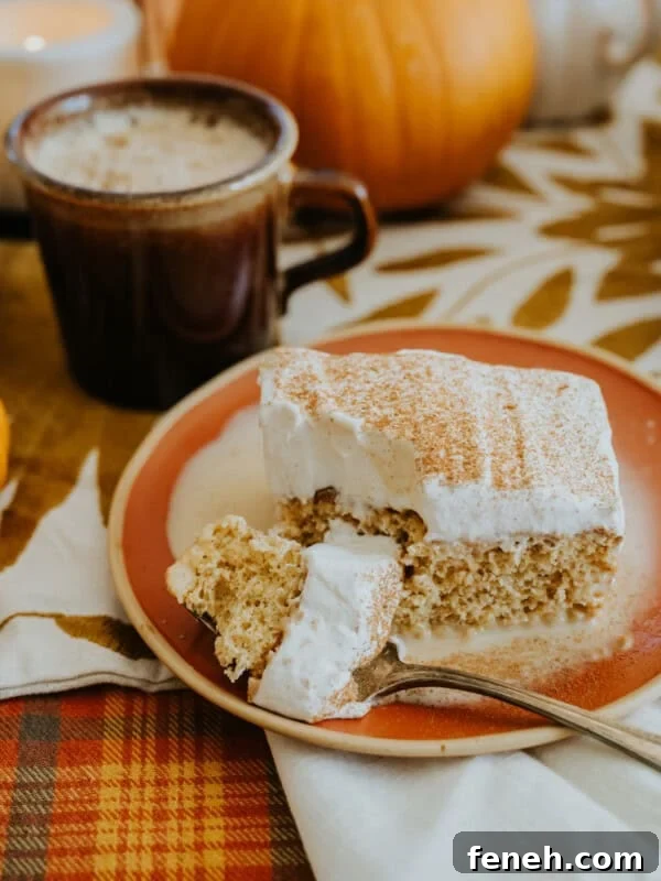slice of pumpkin tres leches cake on a round orange and ecru plate with a silver fork taking a bite out of it and a brown coffee mug in the background.