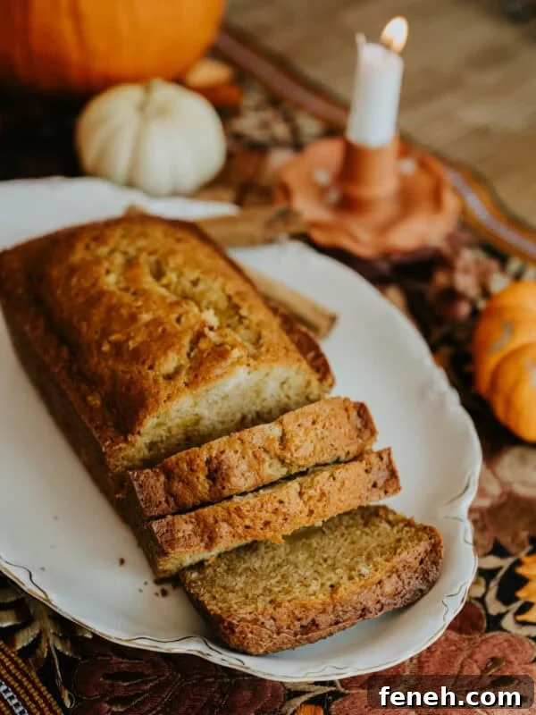 Sliced Mexican pumpkin bread on a white platter with pumpkins in the background.