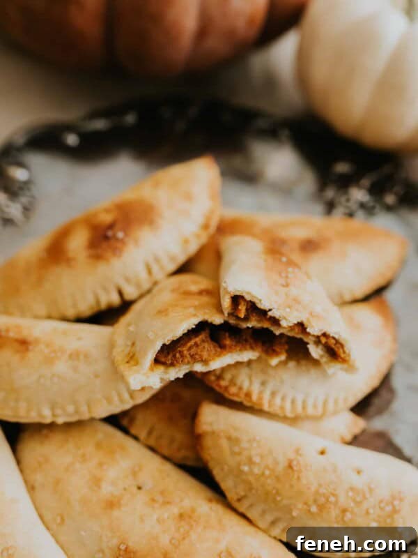pumpkin empanadas stacked up on a silver serving platter.