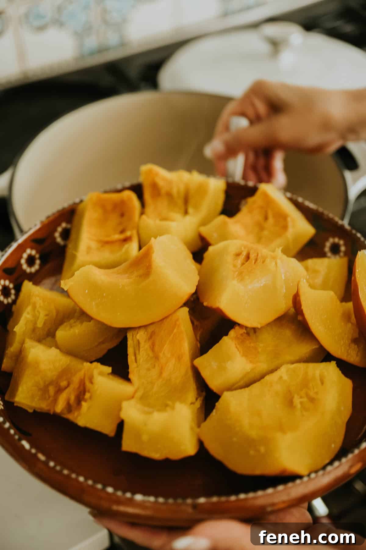 Cooked pumpkin pieces cooling in a clay bowl.