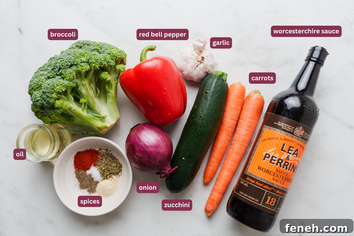 flat lay of ingredients for oven roasted vegetables including broccoli, red bell pepper, garlic, onion. carrots, zucchini, worcestershire sauce, spices, and oil