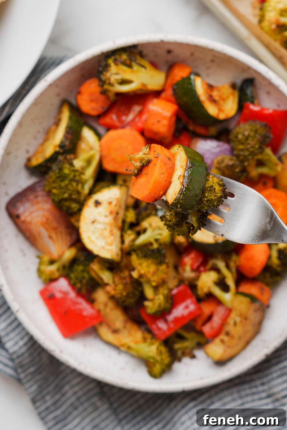 rosted vegetables with grabbed with a fork on top of a bowl.