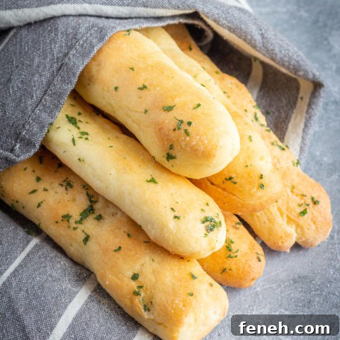 gluten free breadsticks stacked in a pyramid. They are sprinkled with parsley and wrapped in a towel.