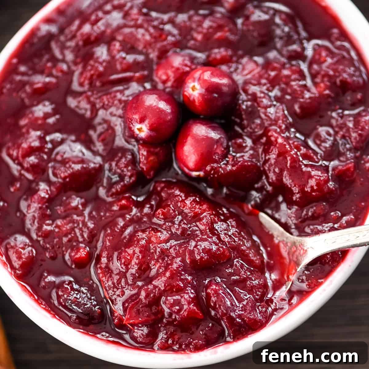 overhead view of a bowl of Healthy Cranberry Sauce with a spoon in it