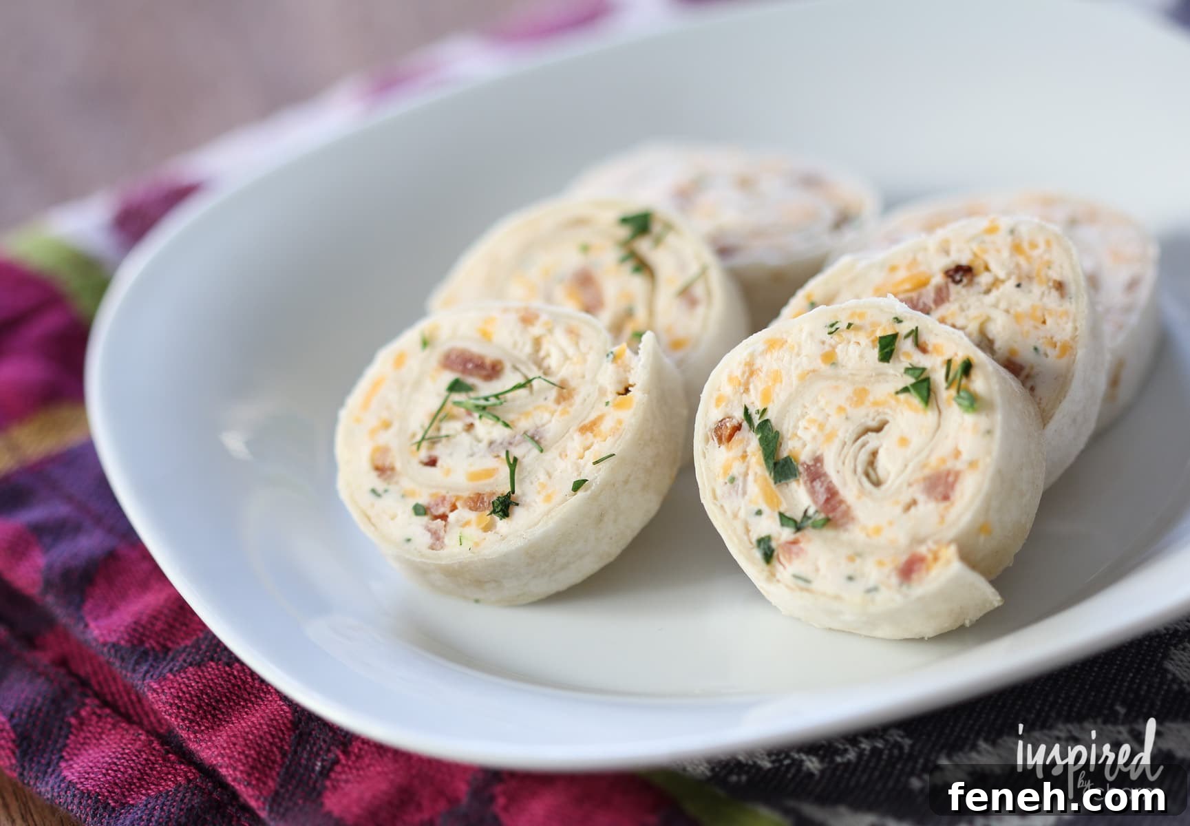 close up of cheddar bacon ranch pinwheels on a small white plate.