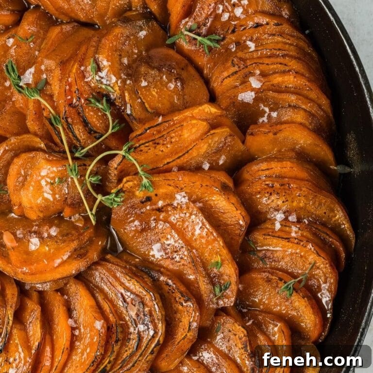 Closeup of orange glazed sweet potato slices in a cast iron skillet.
