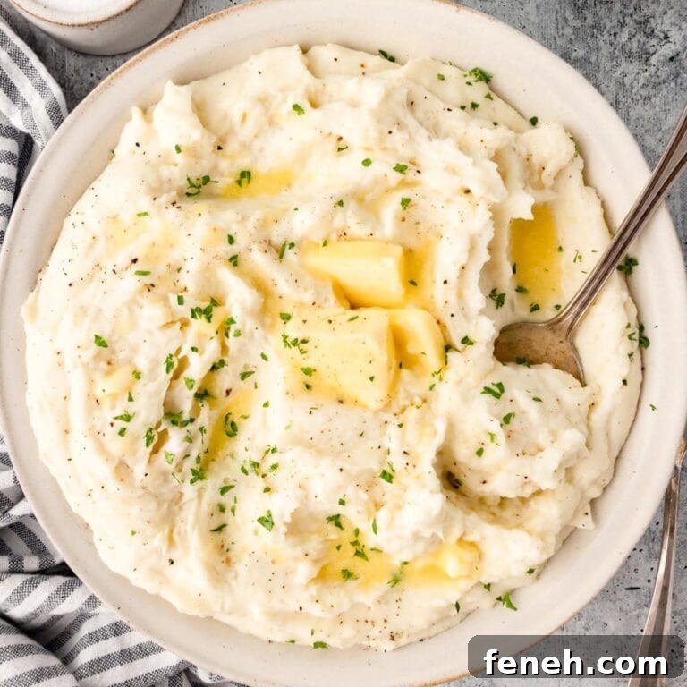 Sour cream mashed potatoes in a serving bowl with serving spoon.
