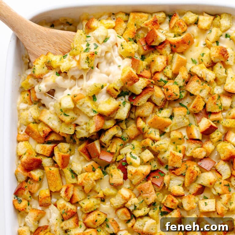 Scoop of gouda mac and cheese being lifted from white casserole dish.