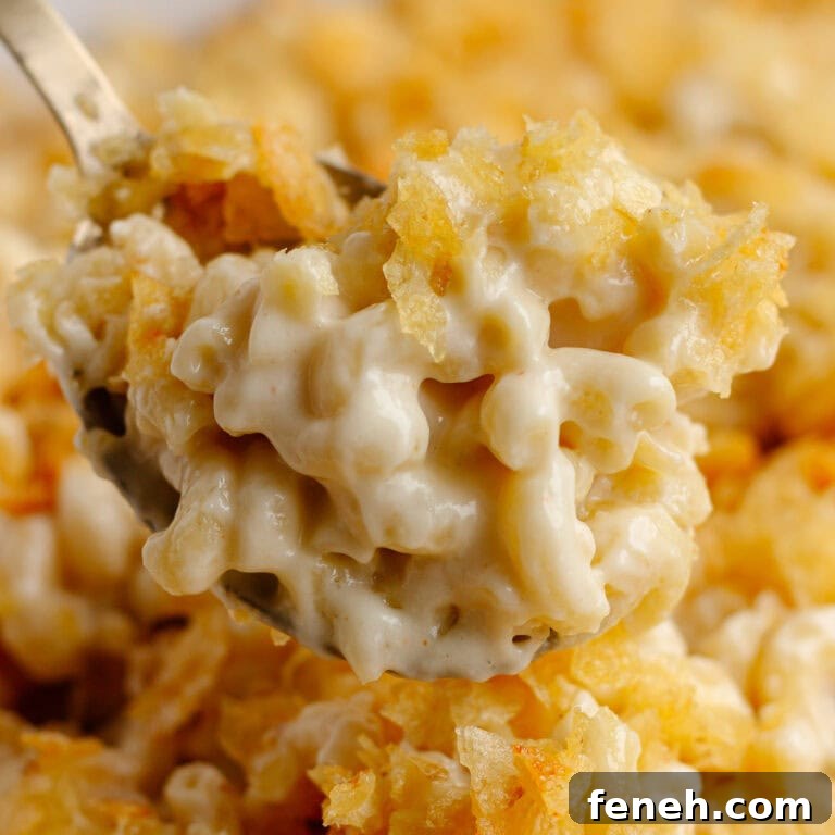 Spoon of white cheddar cheese macaroni and cheese with chip topping.