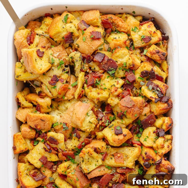 Bacon, sage and onion stuffing in a white casserole dish with serving spoon in corner.