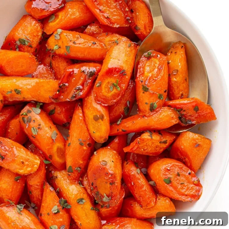 Honey thyme roasted carrots in a white serving dish with serving spoon.