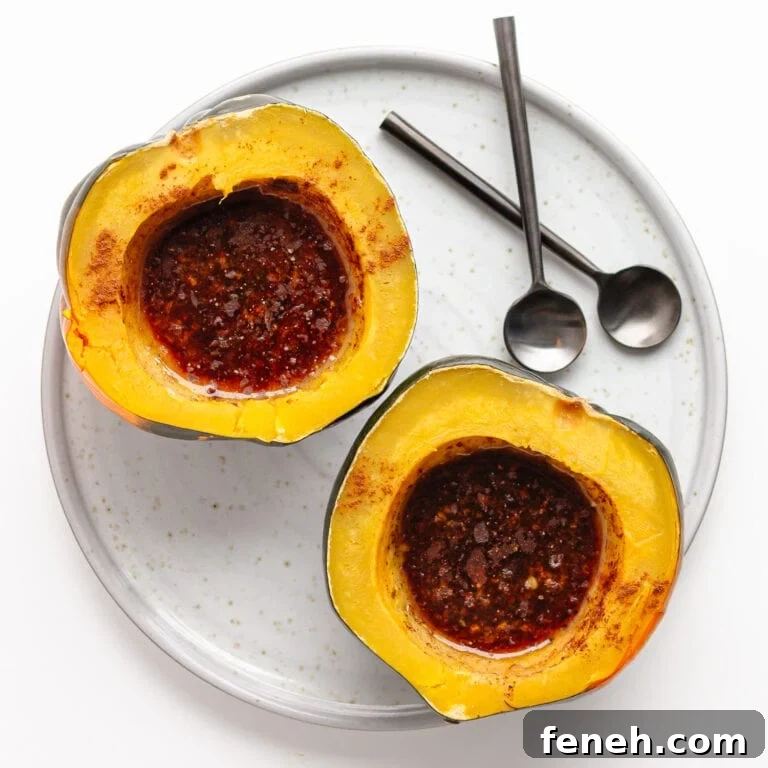 Two pressure cooked acorn squash halves filled with butter and brown sugar topping on a serving plate with two spoons.