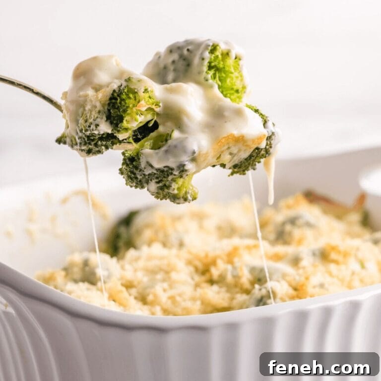 Spoonful of broccoli au gratin being lifted up from white casserole dish.