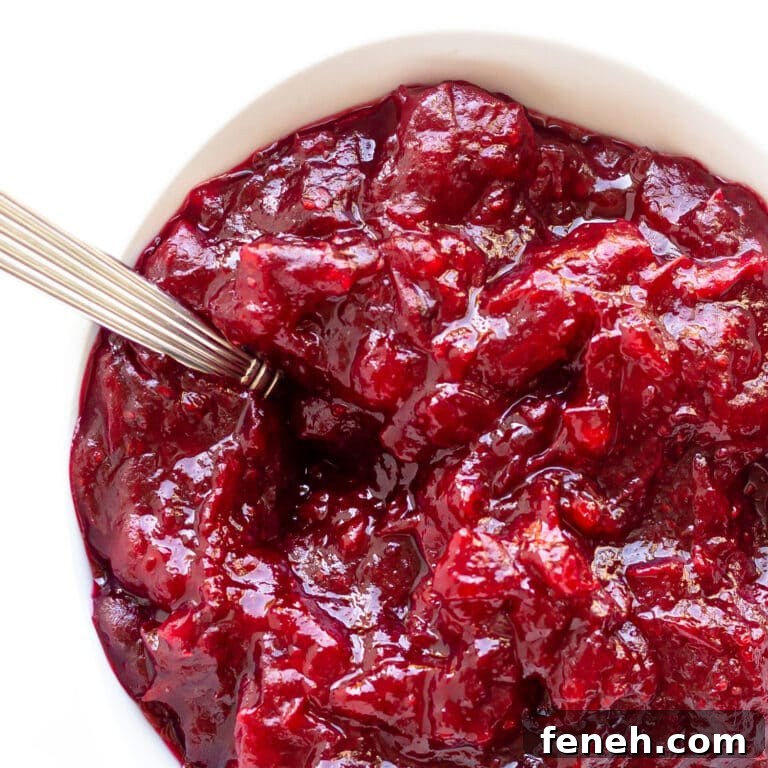 Homemade cranberry sauce in a white bowl with spoon.