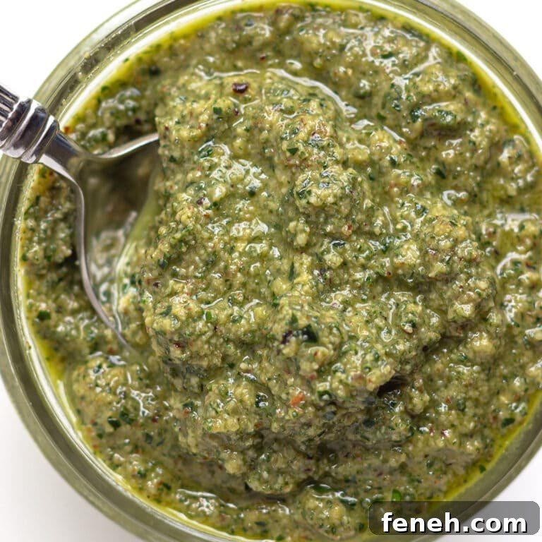 Spoon scooping sage pesto out of a small glass jar.