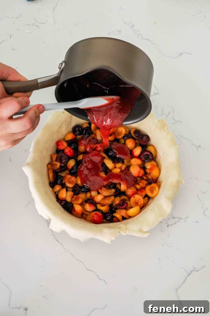 The thickened cherry filling is poured over the cherries in the pie pan.