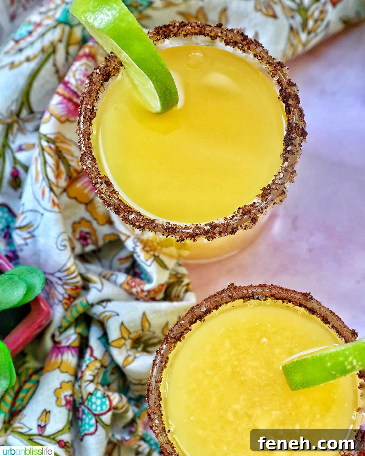 Two spicy mango margaritas with lime garnish and chili rim