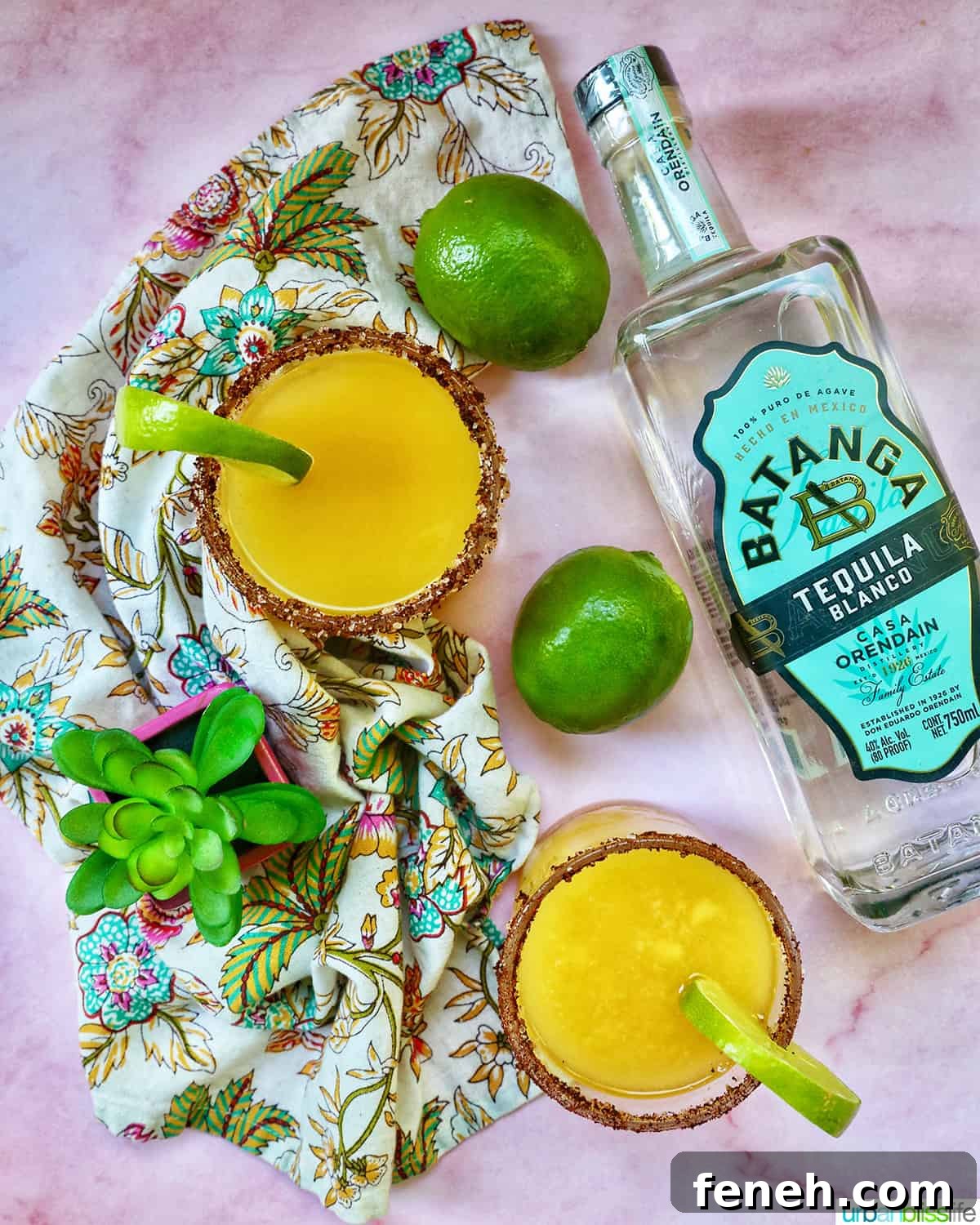 Spicy mango margarita with lime garnish and tequila bottle