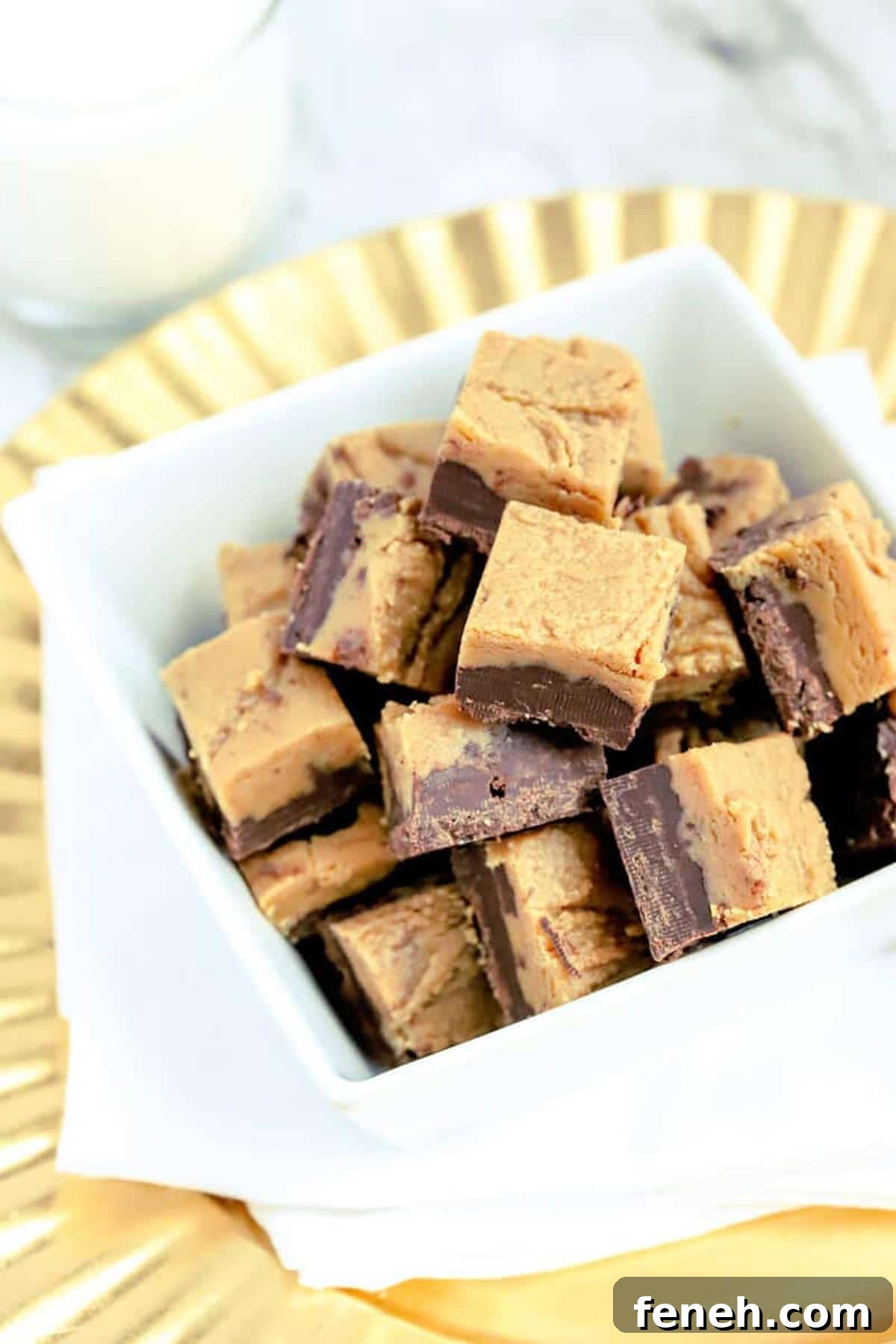 White bowl containing 36 Chocolate Peanut Butter Fudge squares on a gold plate.
