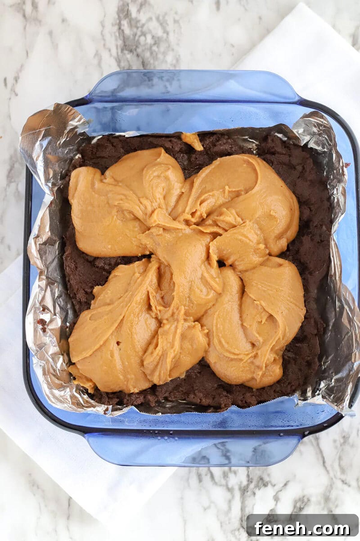 8x8 blue glass dish containing chocolate and peanut butter for making fudge.