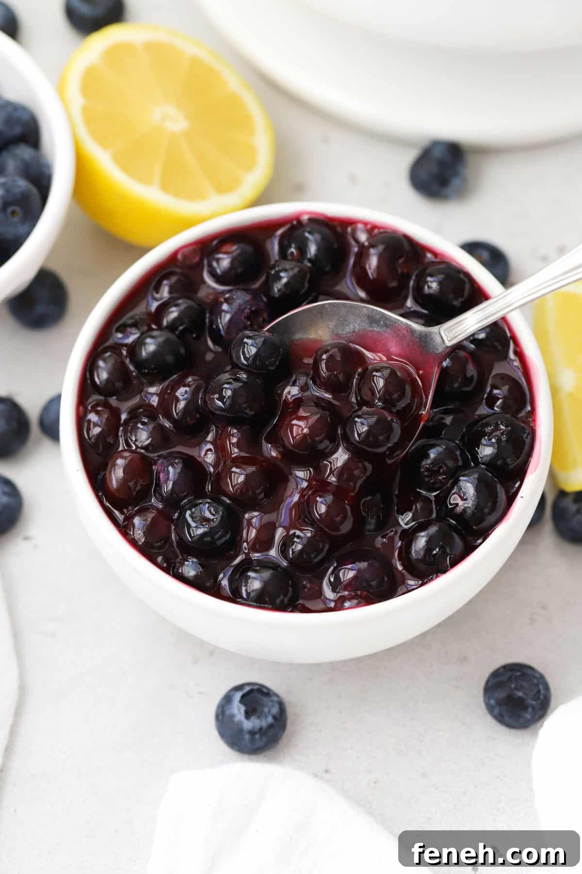 spoon dipping into a bowl of fresh blueberry sauce