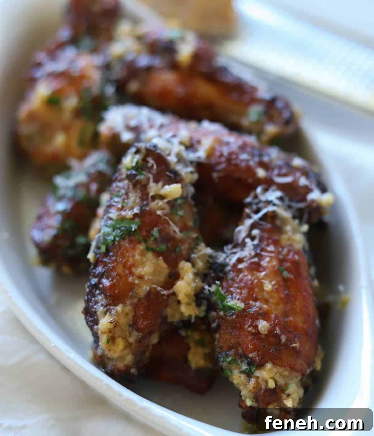 Chicken wings in white dish topped with garlic parmesan sauce.