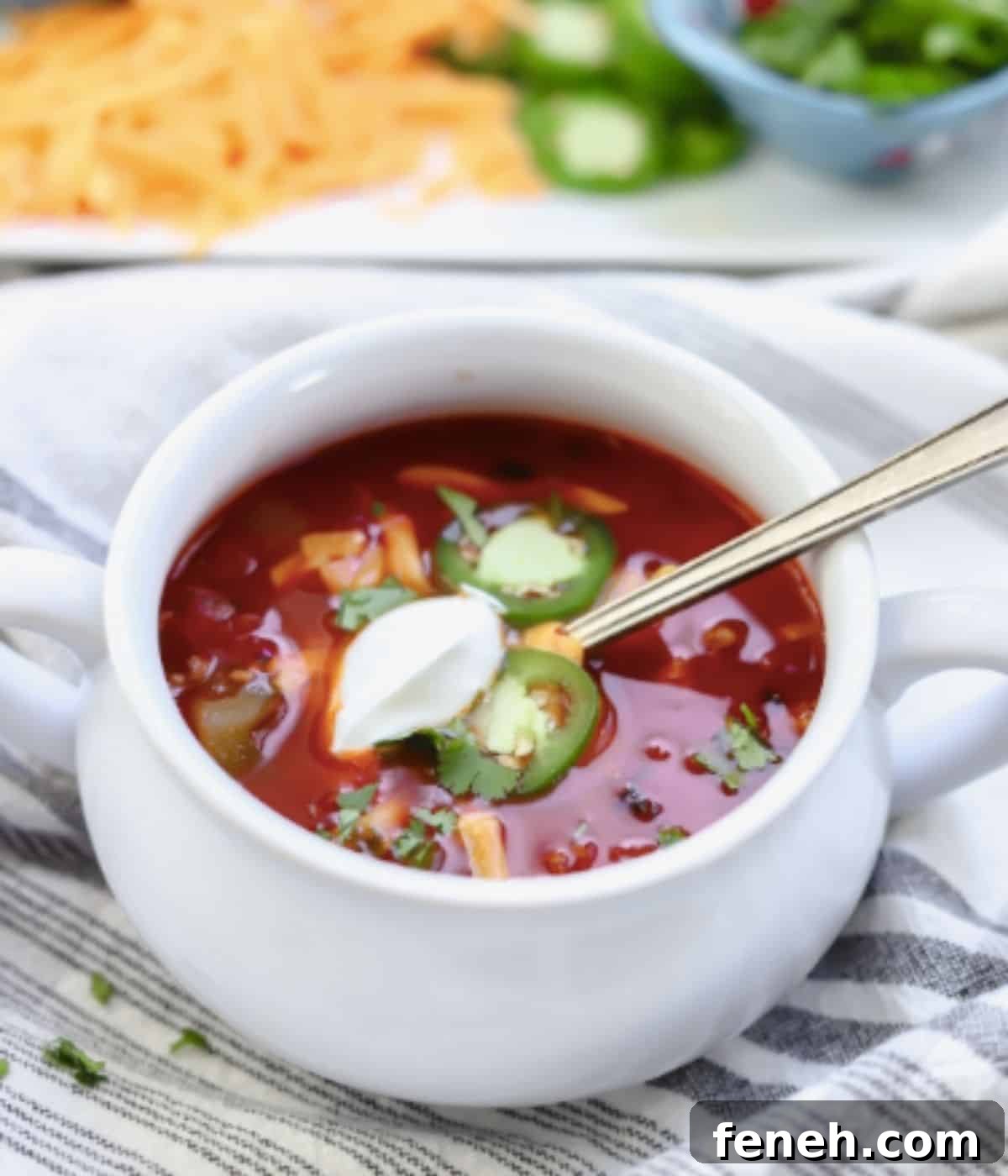 Dutch oven chili in bowl topped with sour cream, cheese and jalapeno