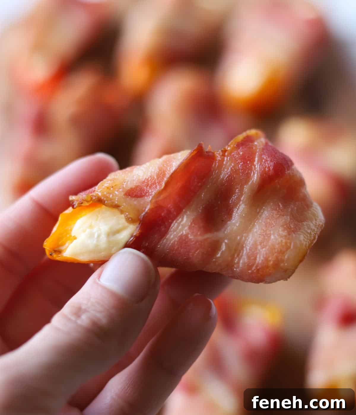 hand holding bacon wrapped stuffed pepper