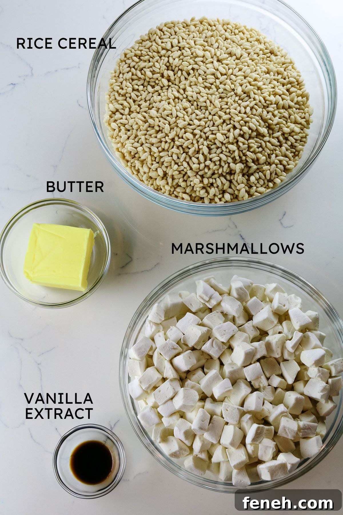 4 bowls on a counter with rice cereal, butter, marshmallows, and vanilla.