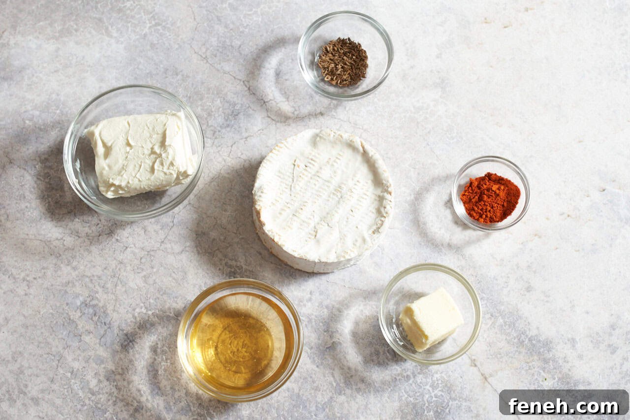 A wheel of camembert cheese surrounded by small bowls of cream cheese, beer, butter, caraway seeds, and paprika.