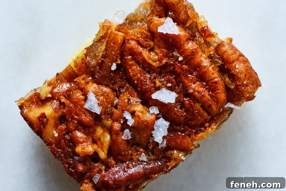 Pecan pie bar with flaky sea salt sprinkled on top on a marble counter.