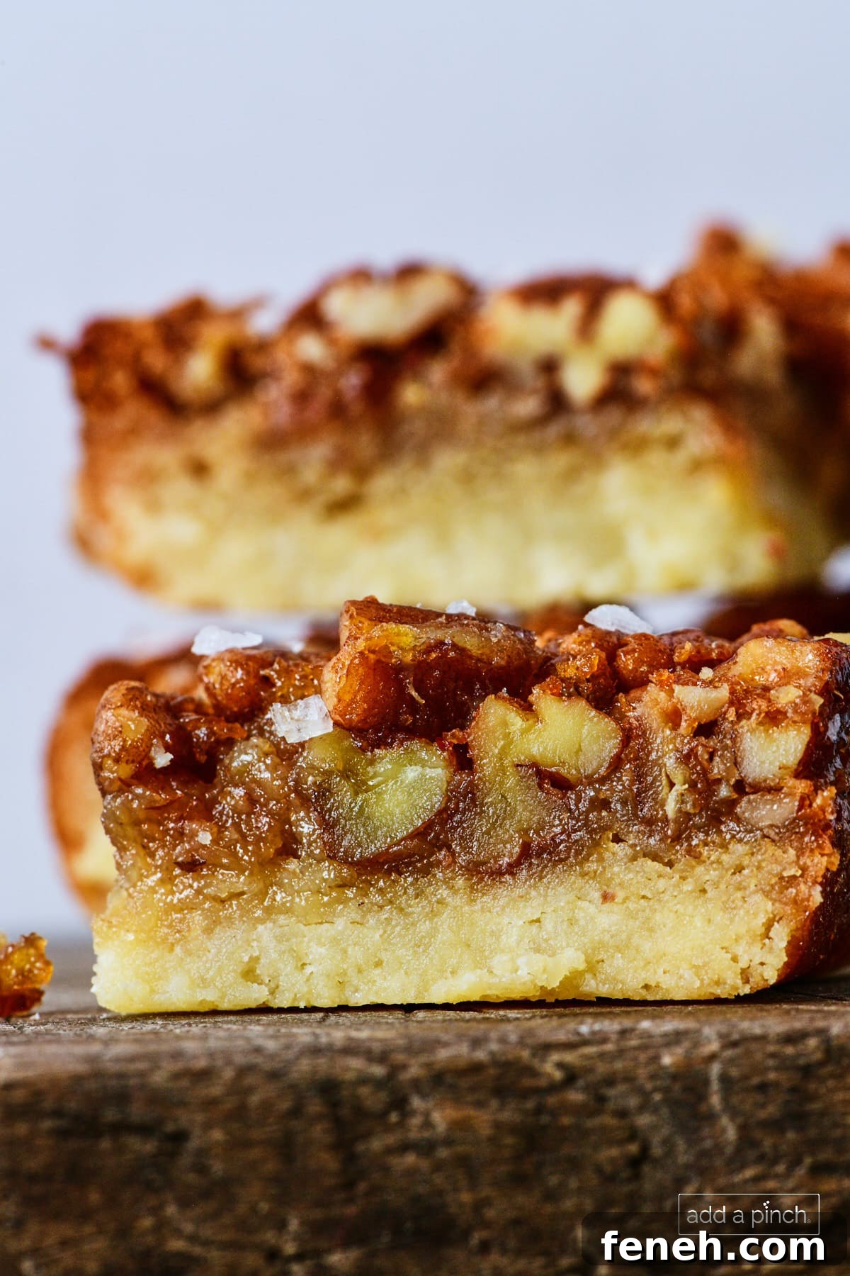 Stack of pecan pie bars on a wooden board.